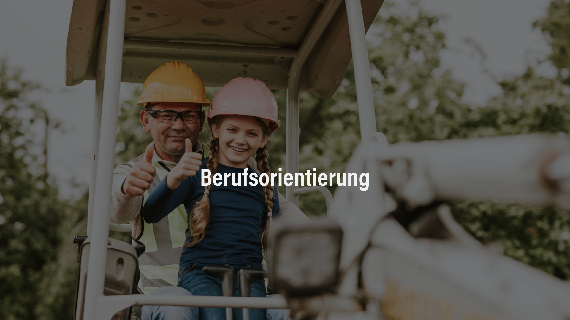 Ein Bauarbeiter mit gelber Schutzweste und Helm sitzt mit einem jungen Mädchen, das einen rosafarbenen Helm trägt, in einer Baumaschine. Beide lächeln und zeigen den Daumen nach oben.