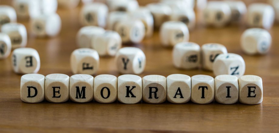 Demokratie Nahaufnahme von Holzbuchstabenwürfeln, die das Wort „Demokratie“ bilden.