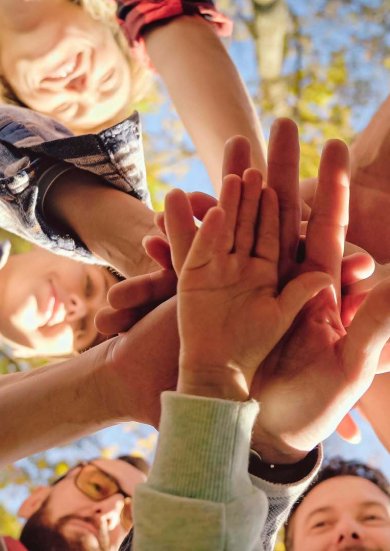 Close up from below on Caucasian activists, men and women with kid putting hand on hand in circle and making gesture of cooperation and coworking. Successful volunteering work together concept.