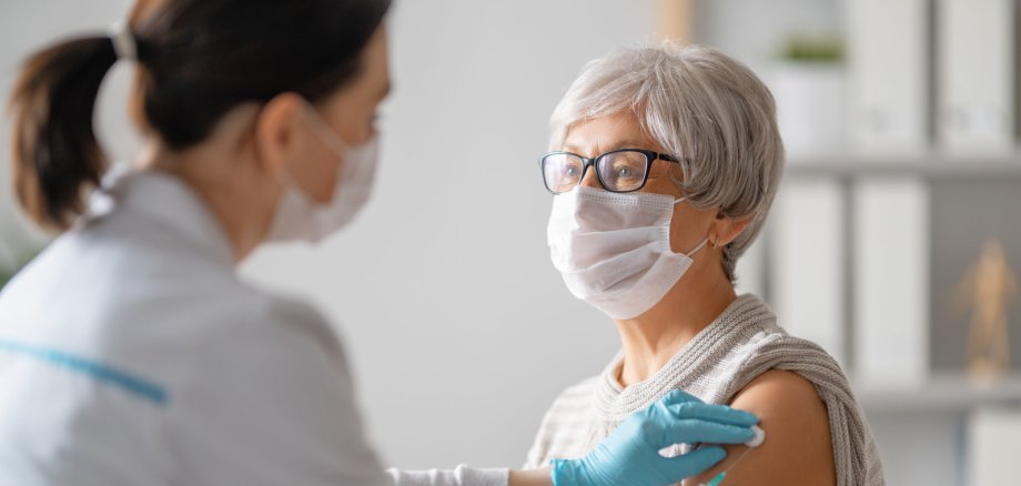 Eine Ärztin impft eine ältere Frau gegen das Corona-Virus.