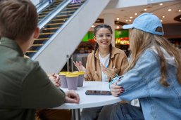 Happy relaxed teenage friends talking sitting in cafeteria of shopping mall Happy relaxed teenage friends talking sitting in cafeteria of shopping mall