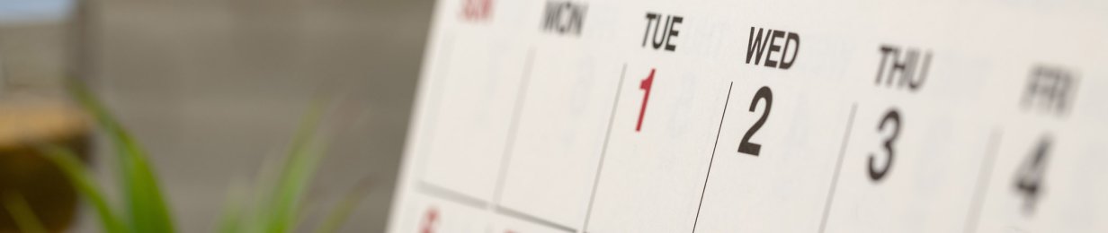 Nahaufnahme eines Teils einer Kalenderseite. Tischkalender steht auf einem Holzschreibtisch.