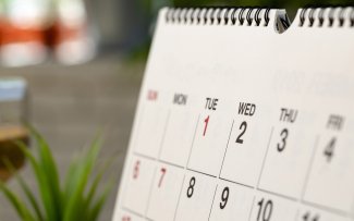 Nahaufnahme eines Teils einer Kalenderseite. Tischkalender steht auf einem Holzschreibtisch.