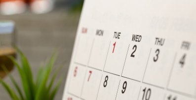 Nahaufnahme eines Teils einer Kalenderseite. Tischkalender steht auf einem Holzschreibtisch.