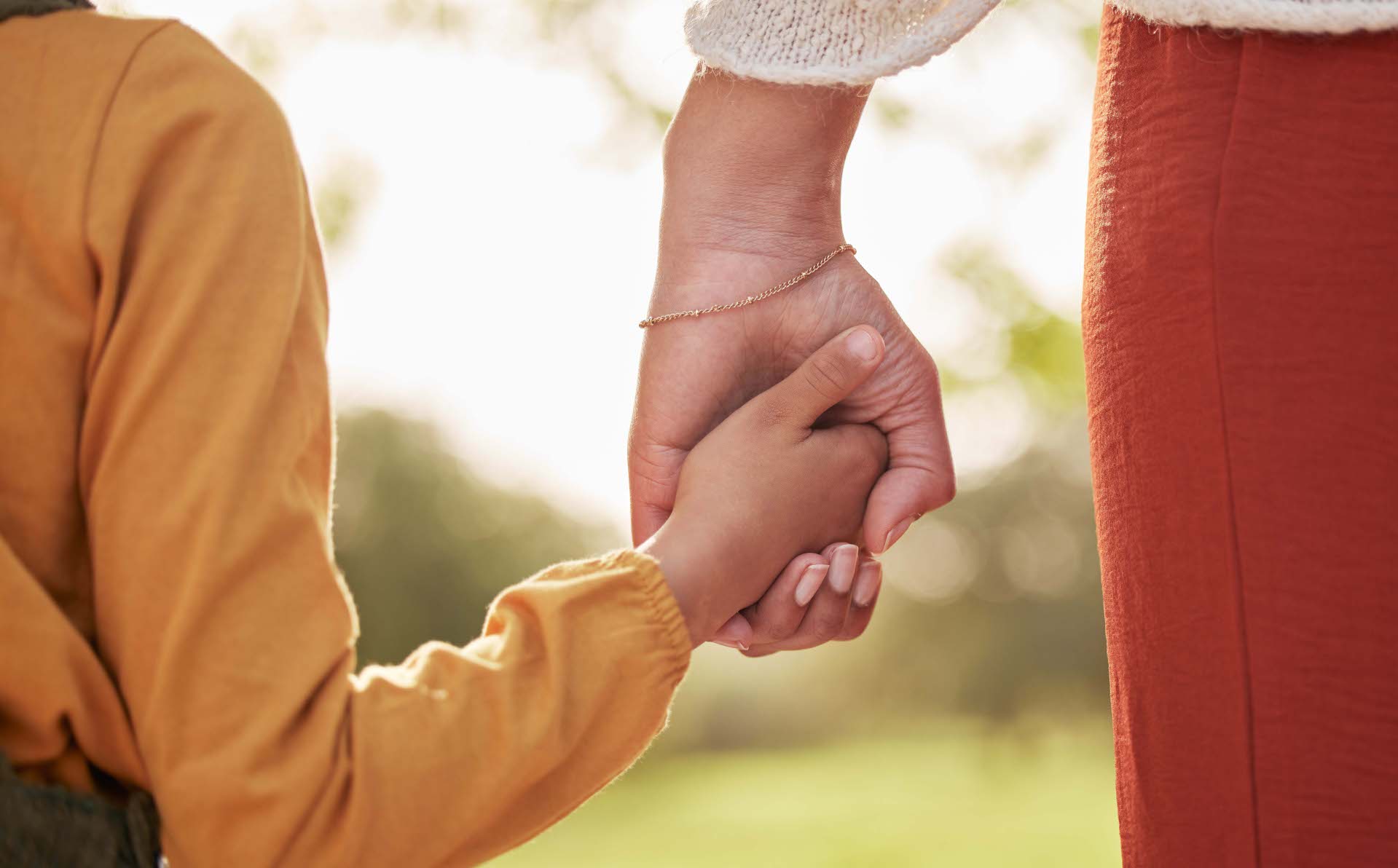 Mutter- und Kinderhand halten einander beim Gehen.