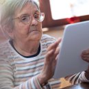 Seniorin mit einem Tablet in der Hand.