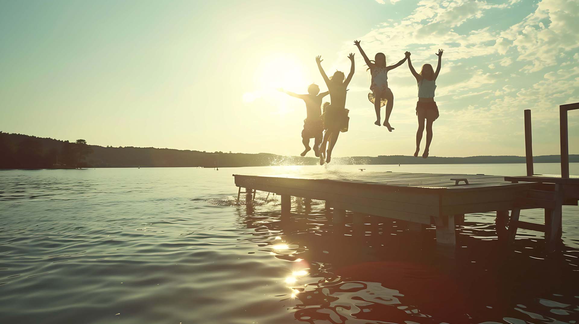 Group of teenage kids jumping off the dock into the lake togethe Group of teenage kids jumping off the dock into the lake togethe