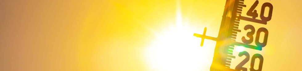 Ein Thermometer zeigt Temperaturen über 30 Grad Celsius an, im Hintergrund scheint grell die Sonne durch einen orange-gelben Himmel.