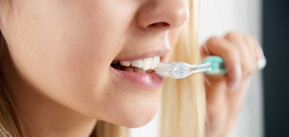 Frau putzt ihre Zähne Eine Frau putzt ihre Zähne. Man sieht den unteren Teil ihres Gesichts und eine Zahnbürste.