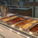 In der Kantine des Landratsamtes in Bad Hersfeld sind warme Speisen zu sehen. Unter anderem sieht man Nudeln, Gemüse, Tomatensoße und Hähnchenschenkel. Im Hintergrund stehen gefüllte Dessertgläser.