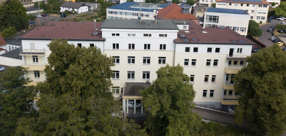 Das Gebäude des Landratsamtes ist aus der Luft zu sehen. Im Hintergrund stehen weitere Häuser. Vor dem Landratsamt sind große Bäume.