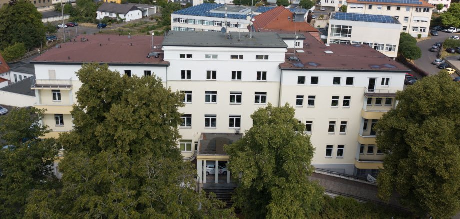 Das Gebäude des Landratsamtes ist aus der Luft zu sehen. Im Hintergrund stehen weitere Häuser. Vor dem Landratsamt sind große Bäume.