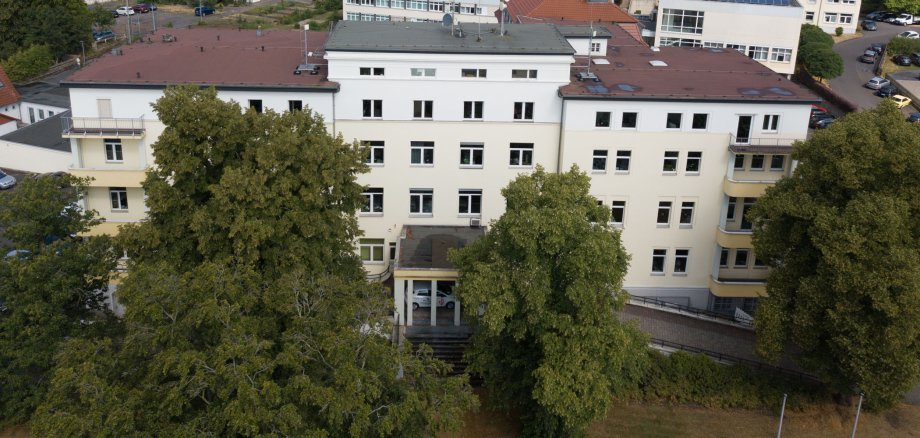 Das Gebäude des Landratsamtes ist aus der Luft zu sehen. Im Hintergrund stehen weitere Häuser. Vor dem Landratsamt sind große Bäume.