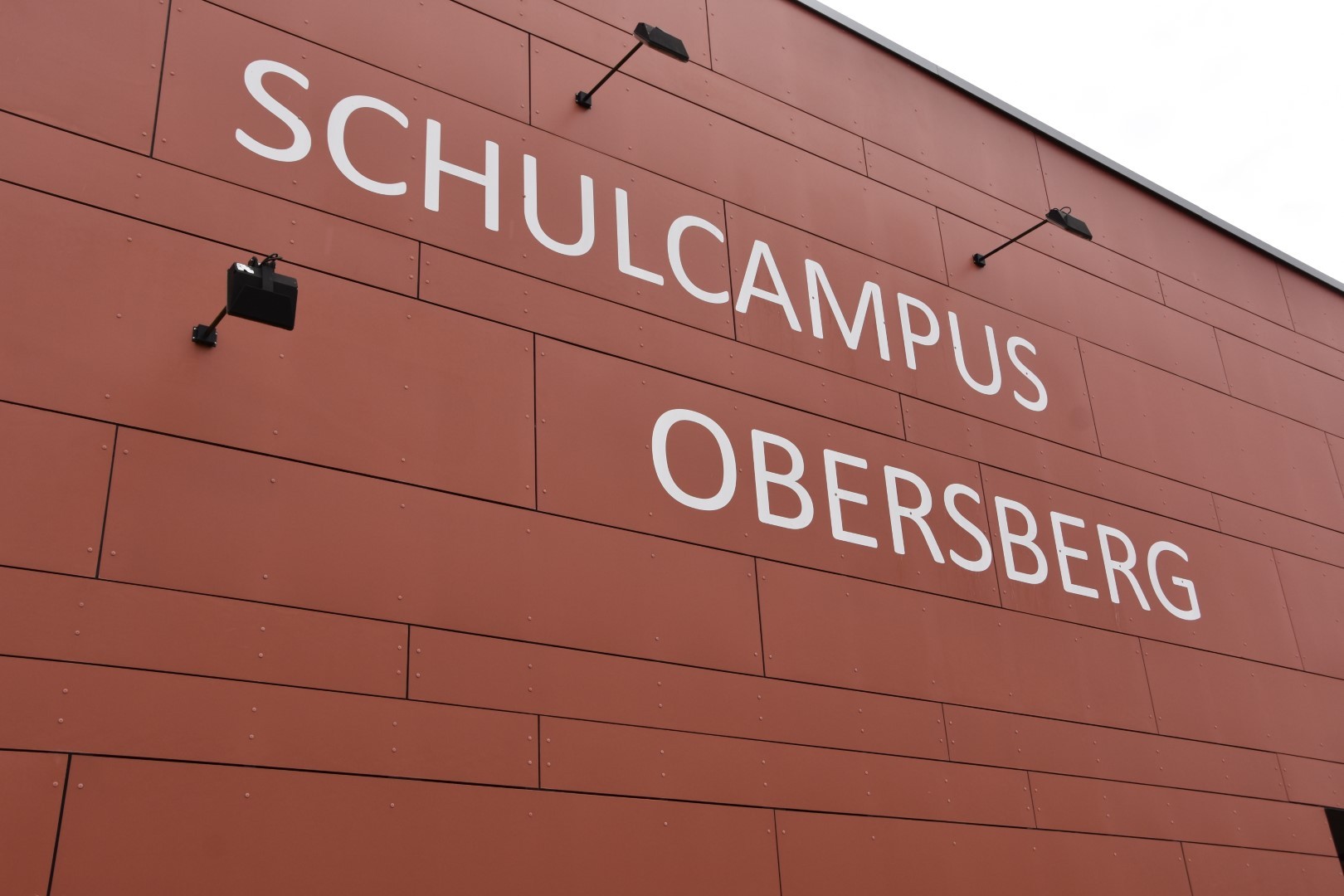 Auf der Außenwand eines Gebäudes steht Schulcampus Obersberg.