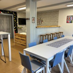 In einem Raum steht eine Tischtafel mit Stühlen. Einige Baarhocker stehen im Raum.
