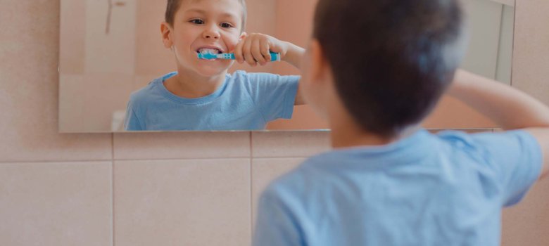 Glückliches Kind putzt sich im Badezimmer die Zähne