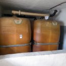 Nahaufnahme von zwei alten, orange-braunen Heizöltanks aus Polyethylen, die in einem Kellerraum stehen.