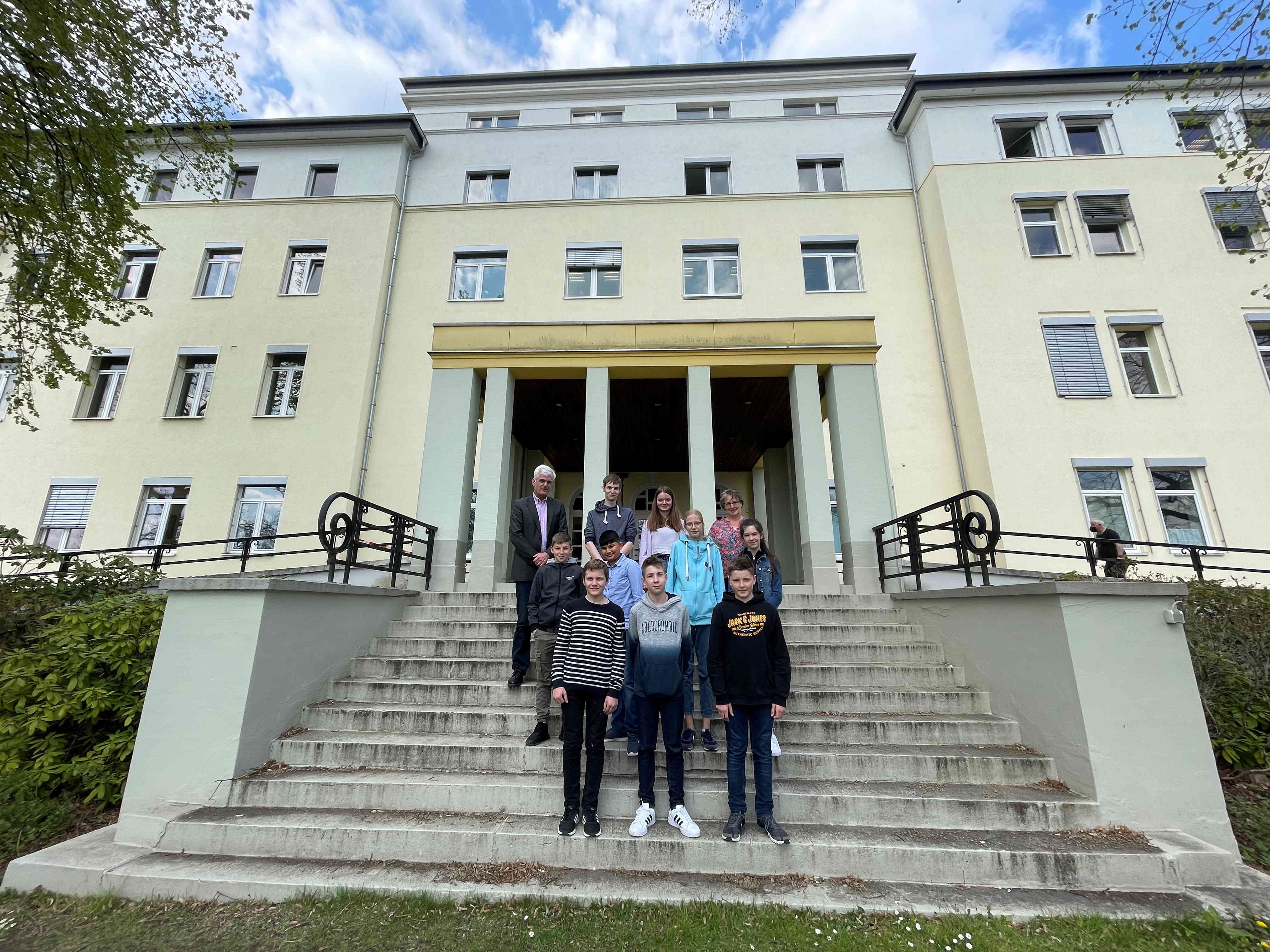 Sieben Schülerinnen und Schüler stehen mit Landrat und Ausbildungsleiterin auf der Treppe vor dem Landratsamt zum Gruppenfoto.