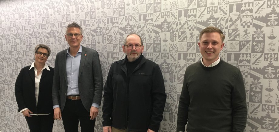 Der Jugendhilfeausschuss bestehend aus Anette Kranz (Leiterin Fachdienst Kinder- u. Jugendhilfe), Dirk Noll (Erster Kreisbeigeordneter), Ralf Bartholmai (Geschäftsführer der Drogenhilfe Nordhessen e.V.) und Julian Gilbert (Verwaltungsleiter des FB Jugend, Soziales und Senioren) stehen vor einer Wand mit Wappentapete.