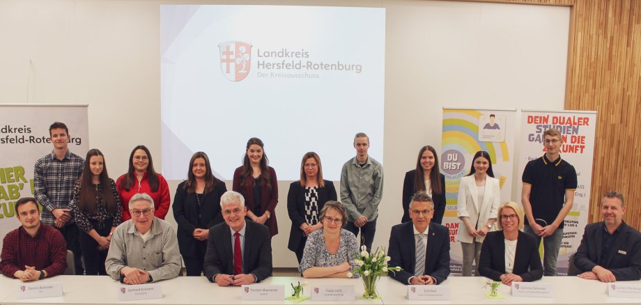 Gruppenbild von jungen Menschen, die hinter einer Gruppe von Sitzenden Mitarbeitern der Kreisverwaltung inklusive des Landrats und seinem Stellvertreter stehen. 