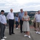 Acht Personen stehen auf dem Bebraer Kirchturm und schauen in die Ferne. Teilweise unterhalten sie sich. Der Himmel ist bewölkt.