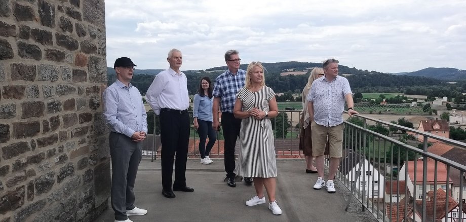 Acht Personen stehen auf dem Bebraer Kirchturm und schauen in die Ferne. Teilweise unterhalten sie sich. Der Himmel ist bewölkt.