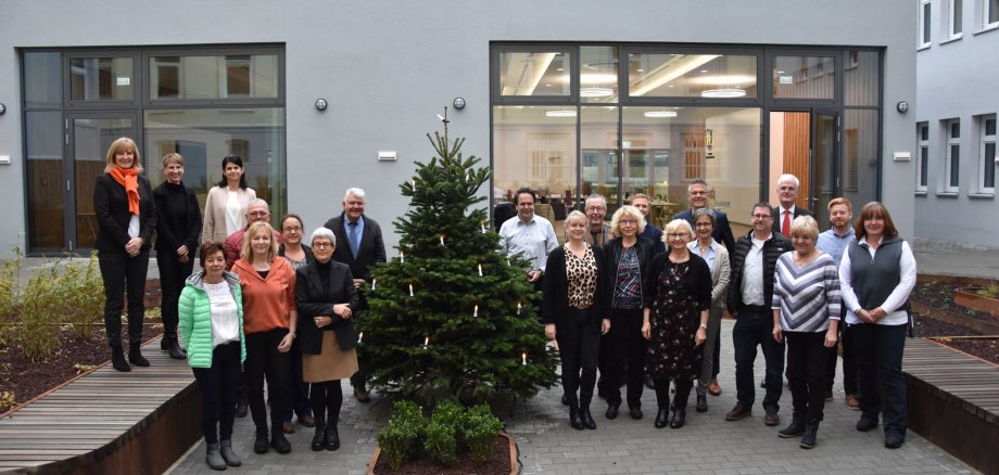 Geehrte Mitarbeiterinnen und Mitarbeiter der Kreisverwaltung stehen mit den Verwaltungschefs in einer Gruppe im Innenhof des Landratsamtes und schauen in die Kamera.