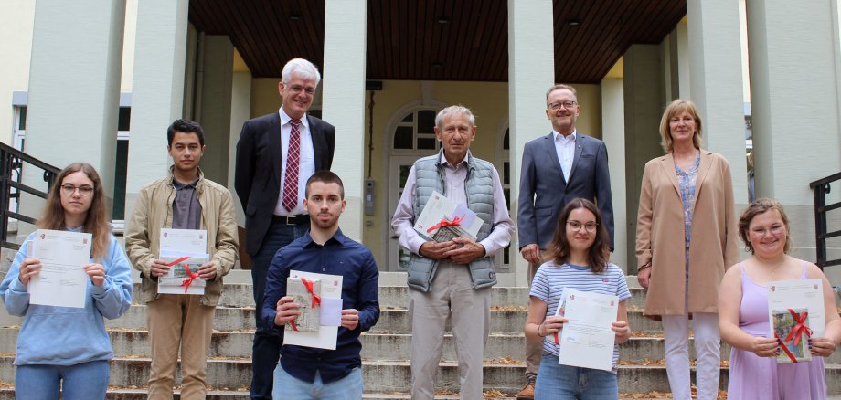 Einige Schülerinnen und Schüler und Mitarbeitende des Landratsamtes, darunter auch Landrat Warnecke, stehen auf der Treppe vor dem Haupteingang der Kreisverwaltung. Die Schülerinnen und Schüler halten eine Urkunde und ein Geschenk.