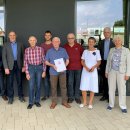 Teilnehmer der Ortslandwirte-Tagung stehen vor einem Gebäude. Ein Teilnehmer hat eine Urkunde in der Hand.