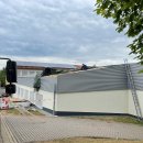 Das Dach einer Schule ist beschädigt. Ein Mann sitzt auf dem Dach und arbeitet daran. 
