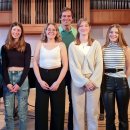 Fünf Musikschülerinnen stehen in einer Reihe auf einer Bühne. Hinter ihnen steht Timo Wichmann, Leiter der Musikschule des Landkreises Hersfeld-Rotenburg. Im Hintergrund sieht man eine Orgel.