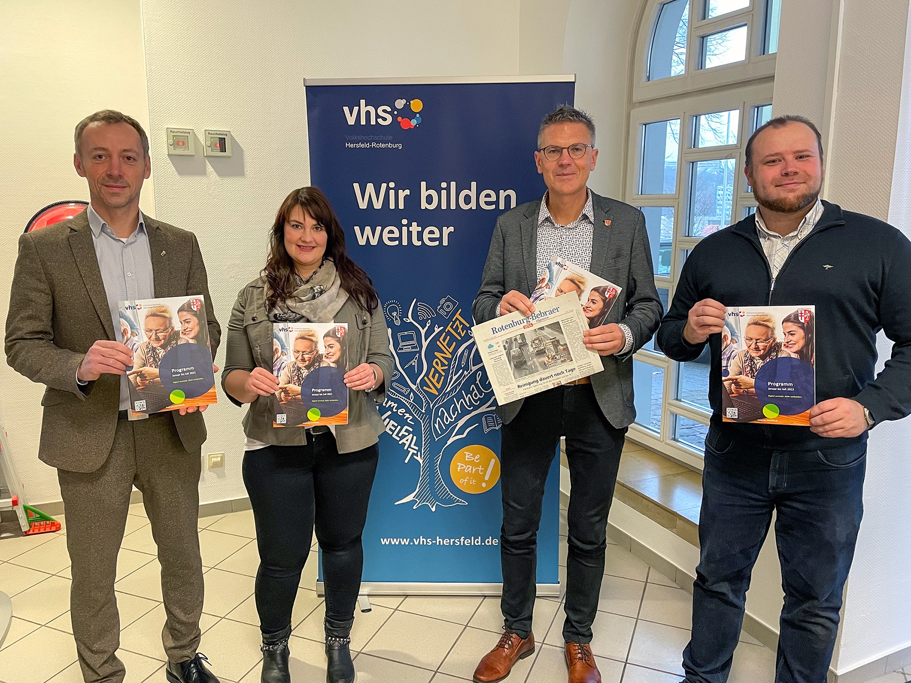 Erster Kreisbeigeordneter Dirk Noll, VHS-Leiter Fabian Goebel und zwei Mitarbeitende der VHS halten das neue VHS Programm im Landratsamt.