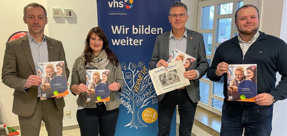 Erster Kreisbeigeordneter Dirk Noll, VHS-Leiter Fabian Goebel und zwei Mitarbeitende der VHS halten das neue VHS Programm im Landratsamt.