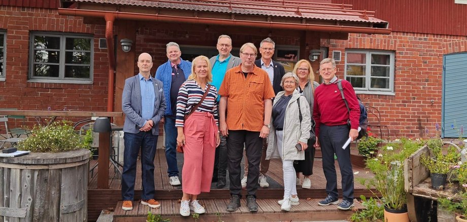 Eine Gruppe aus finnischen und deutschen Menschen steht vor dem Musterbauernhof von Familie Eerola in Hyvinkää, der finnischen Partnerregion des Landkreises Hersfeld-Rotenburg.