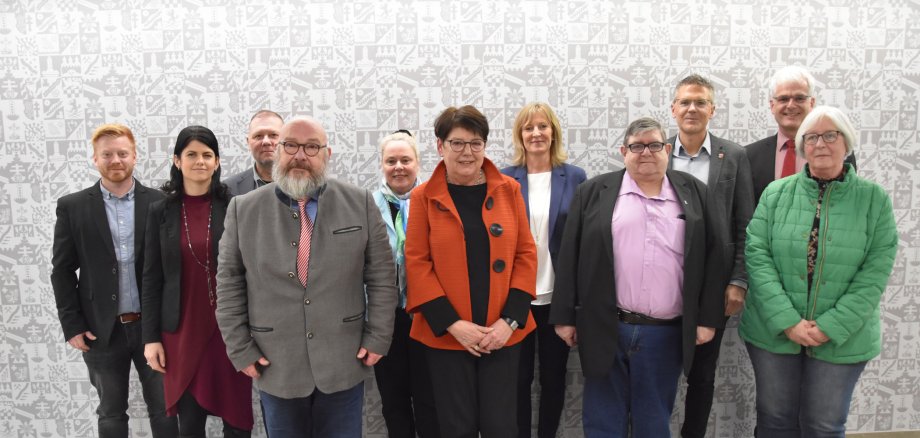 Einige Personen stehen vor einer Wappen-Tapete im Landratsamt in Bad Hersfeld.