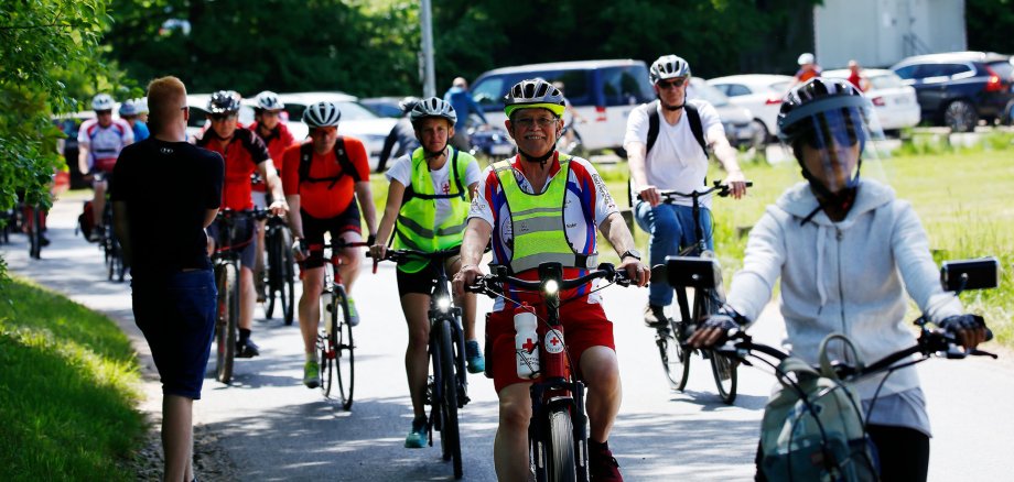 Viele Radfahrerinnen und Radfahrer fahren auf einem Fahrradweg. Das Wetter ist schön. Sie lächeln und haben Spaß. Sie nehmen an einer Tour des Stadtradelns 2022 teil.