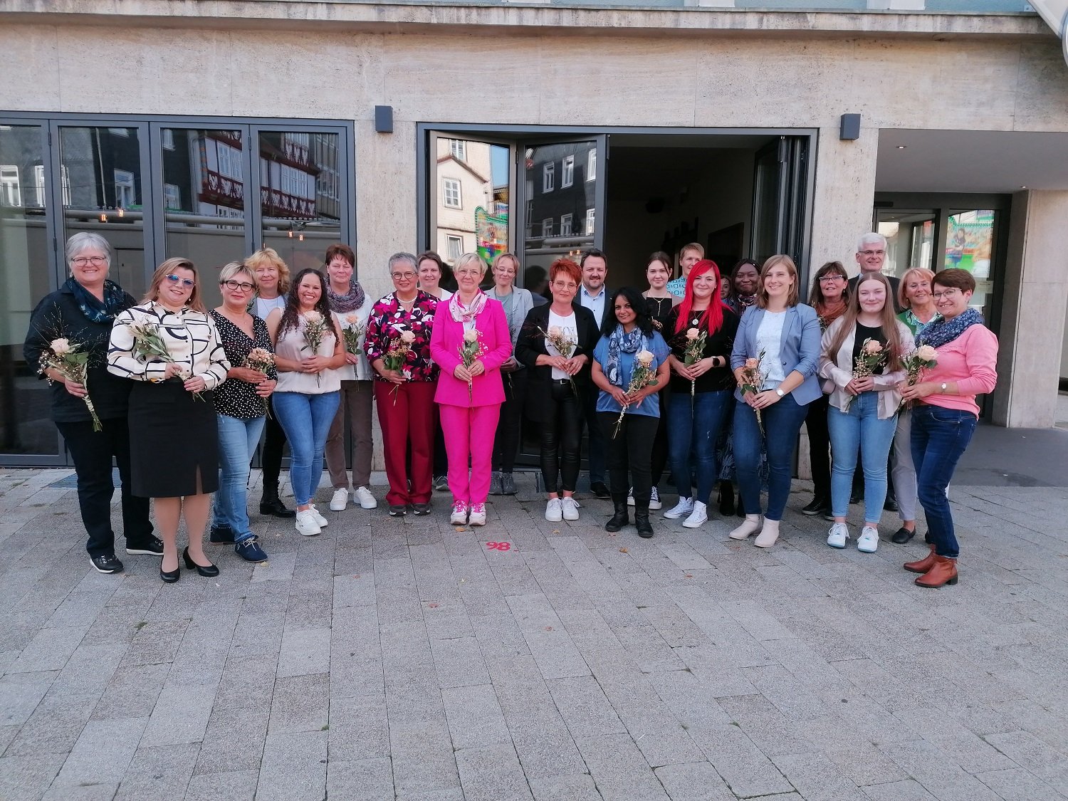 Viele Frauen und einige Männer stehen vor dem Bad Hersfelder News-Café. Die geehrten Mitarbeitenden der Kreisaltenpflege Hersfeld-Rotenburg halten jeweils eine Rose in der Hand. Alle lächeln.