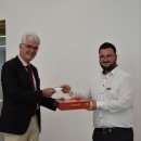 Landrat Torsten Warnecke übergibt einem Auszubildenden ein Spiel und erhält dafür eine Tauschkarte. Die beiden stehen im Kreistagssitzungssaal der Verwaltung.
