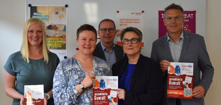 Zwei Vertreterinnen von pro Familia sowie drei Vertreter vom Landkreis Hersfeld-Rotenburg stehen in der Geschäftsstelle von pro familia. Sie halten ein Plakat des Projektes HALTE.PUNKT.