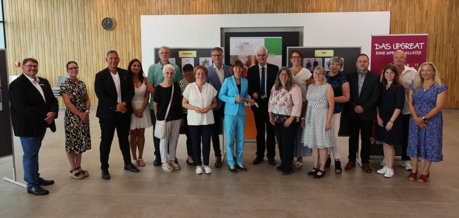 Rund 20 Personen stehen im Kreistagssitzungssaal der Kreisverwaltung. Sie lächeln und stehen in einer Gruppe.