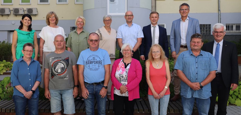 Einige Mitarbeitende der Kreisverwaltung stehen im Innenhof des Landratsamtes. Sie lächeln in die Kamera. Im Hintergrund sieht man Fenster und Pflanzen.