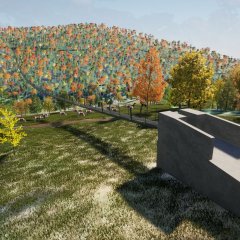 Eine Betonstruktur mit einem Rampenweg und einer darauf verlaufenden Hängebrücke inmitten einer grünen, hügeligen Landschaft mit Bäumen. Im Hintergrund sind Autos geparkt und Personen sind auf der Brücke zu sehen.