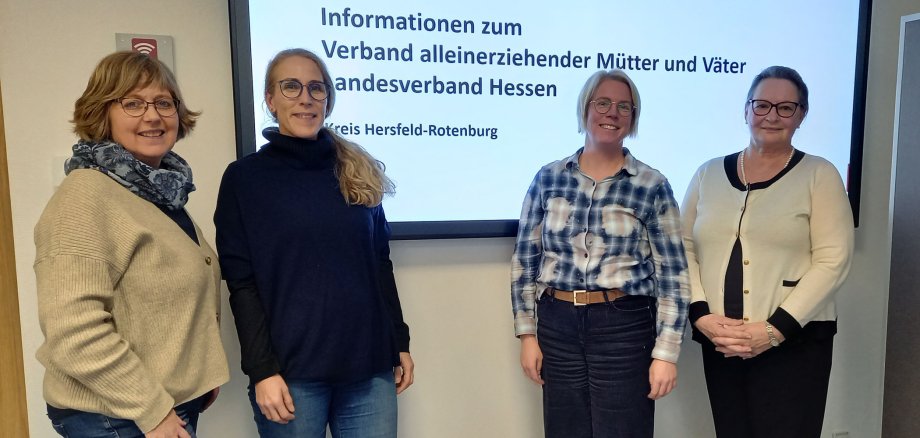 Vier Frauen stehen vor einer Power-Point-Präsentation in einem Besprechungsraum. Sie gehören dem Netzwerk Alleinerziehende an.