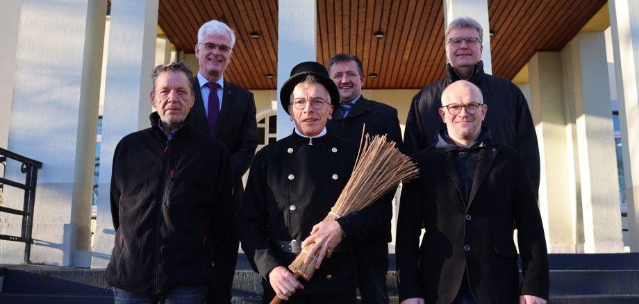 Mehrere Männer stehen auf der Treppe vor dem Landratsamt. Unter ihnen auch einer in einer Schornsteinfeger-Uniform.