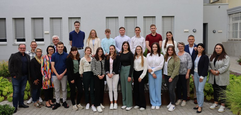 Die neuen Studierenden und Auszubildenden der Kreisverwaltung stehen mit der Verwaltungsleitung und den Personalvertretungen im Innnenhof der Kreisverwaltung. Sie freuen sich.