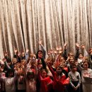 Viele Kinder stehen vor dem Vorhang in einem Kino-Saal