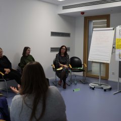 In einem der Besprechungsräume im Landratsamt sitzt eine Gruppe aus mehreren Teilnehmenden. An der Wand steht ein Flipchart.