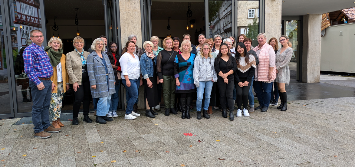 Mehrere Personen stehen vor dem News-Café in der Bad Hersfelder Innenstadt. Sie schauen in die Kamera. Der Boden ist feucht.