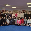 Eine große Gruppe von Jugendlichen und Erwachsenen steht und kniet in einer Sporthalle mit blauen Matten für ein gemeinsames Gruppenfoto. Vorne befinden sich Karate-Trainer in weißen Karateanzügen, während die Teilnehmer in sportlicher Kleidung dahinter stehen. Links informiert ein Banner über das „Freiwillige Soziale Schuljahr Hessen“ im Landkreis Hersfeld-Rotenburg, rechts ist ein Banner des Karate-Dojo Rotenburg e.V. zu sehen.