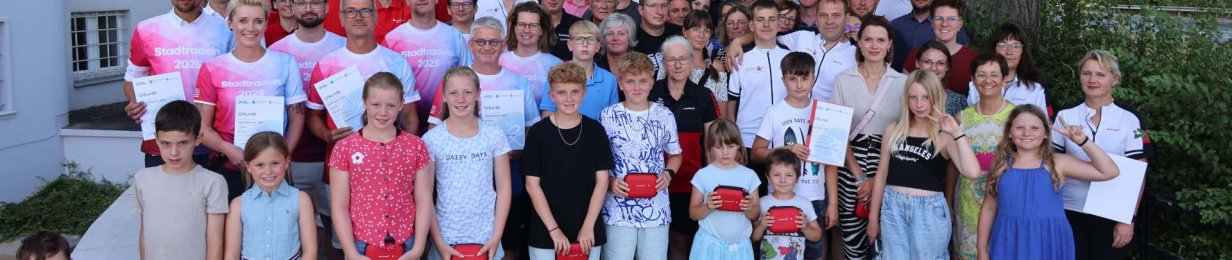 Große Gruppe aus Kindern und Erwachsenen bei der Siegerehrung des Stadtradelns vor dem Landratsamt Hersfeld-Rotenburg. Einige Personen halten Urkunden oder Preise in der Hand.